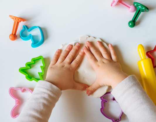 Food for Thought Therapy | Success in Feeding Therapy Beyond Food Expansion | Color image of child's hands playing with white playdoh with cookie cutters surrounding